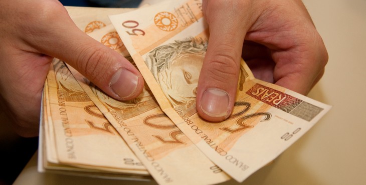 O que fazer com o 13º salário? Descubra agora! Crédito - mão emprestando dinheiro